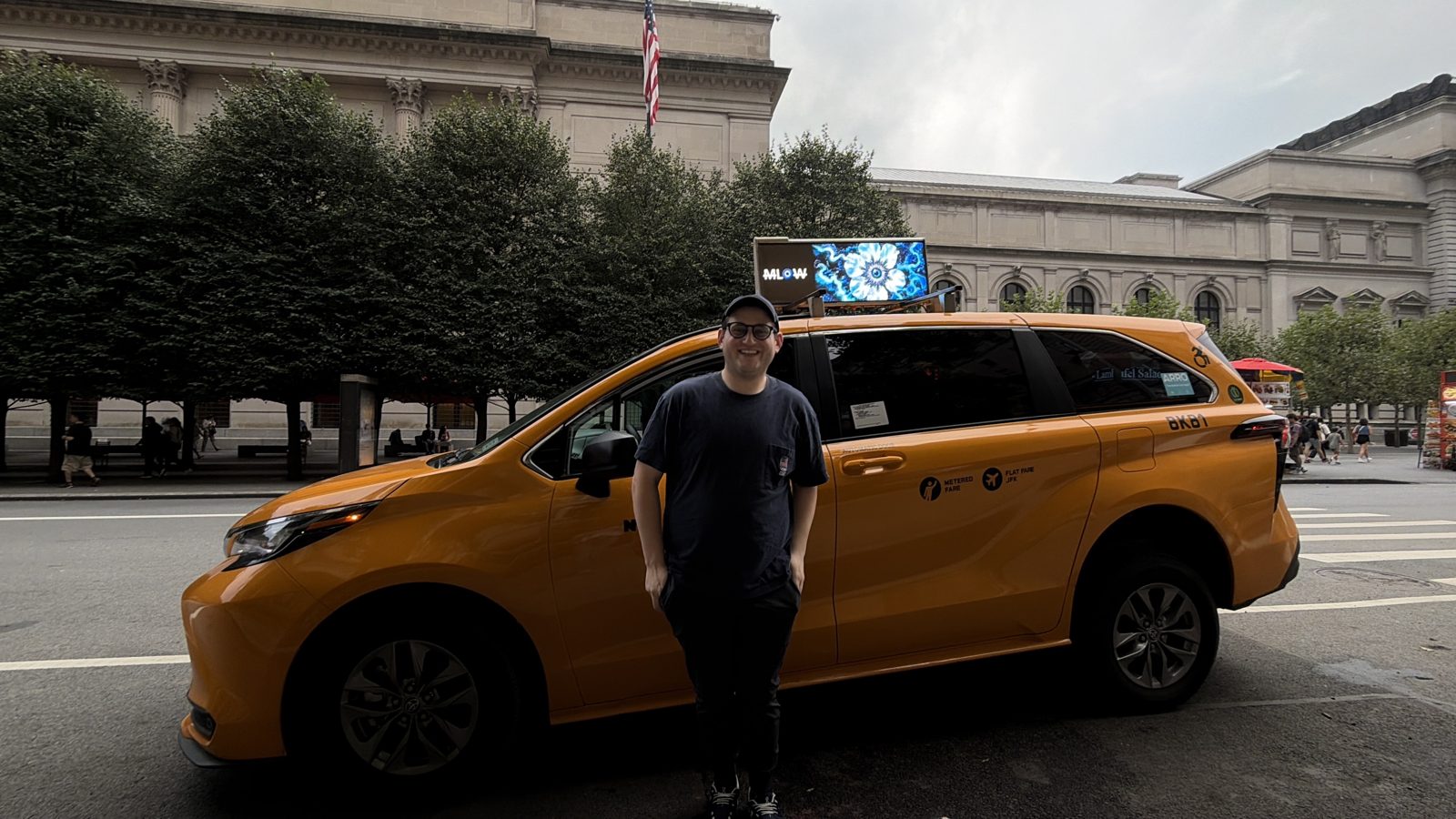 MLow standing beside a New York taxi outside The Met, his flower-headed figure on the taxi top