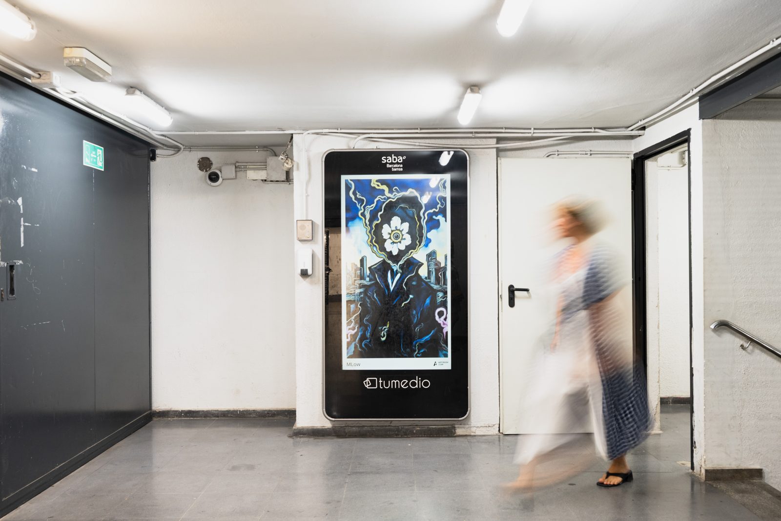 MLow's flower-headed figure on a TuMedio screen in a Barcelona car park